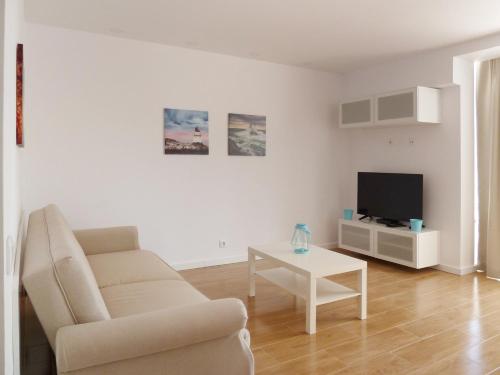 a living room with a couch and a tv and a table at Ocean Breeze Apartment in Estoril