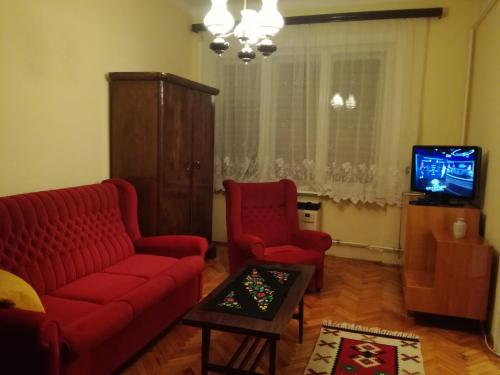ミシュコルツにあるSzatmari Apartmanのリビングルーム(赤いソファ2台、テレビ付)