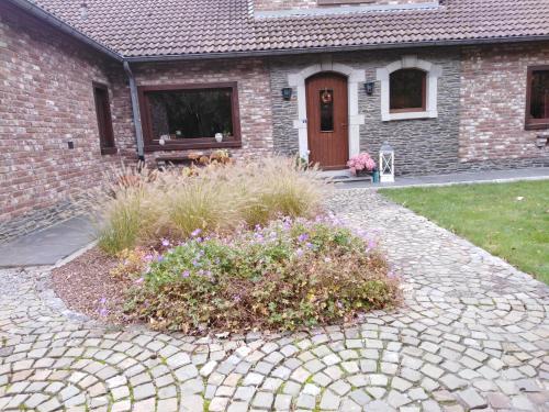 a brick house with a stone driveway in front of a yard at Chez YOYO in Stavelot