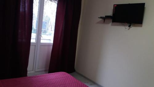 a bedroom with a tv and a window with a curtain at Central Studio in Ternopilʼ