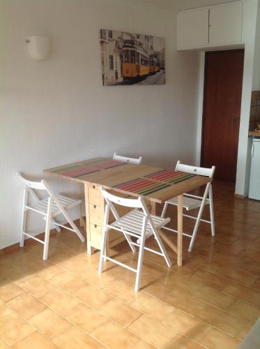 a dining room table with white chairs around it at Beach apartment... T1 with swimming pool (summer) in Costa da Caparica
