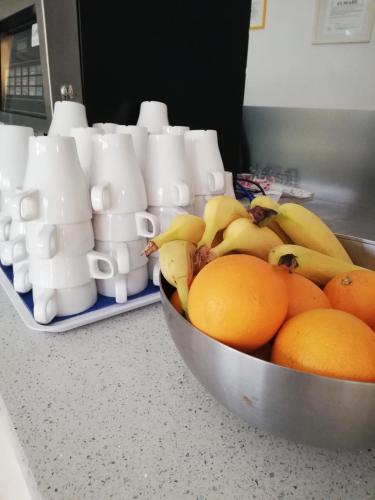 a bowl of oranges and bananas on a counter with cups at Ahr Hotel Villa Alighieri in Stra