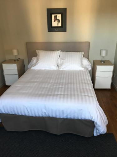 une chambre avec un grand lit blanc avec deux tables de nuit dans l'établissement Appartement de 100m² bien situé, à Boulogne-sur-Mer