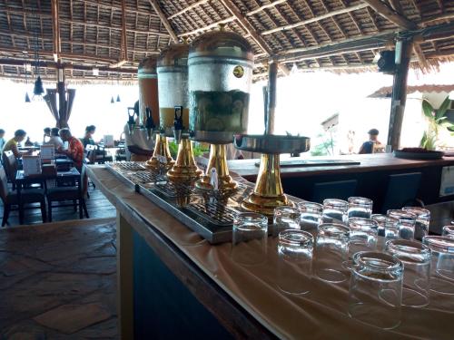 a bar with glasses on a counter in a restaurant at Amaan Beach Bungalows in Nungwi