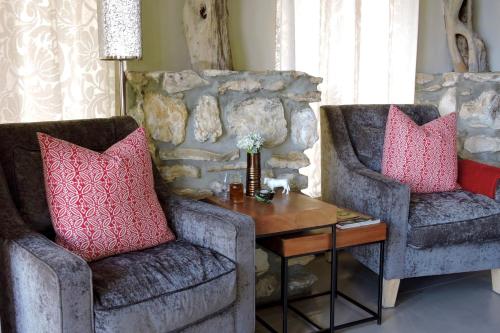 two chairs and a table in a living room with pink pillows at Mosaic Lagoon Lodge in Stanford