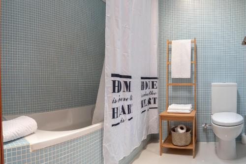 a bathroom with a tub and a toilet and a shower curtain at Azuleixo in Aveiro