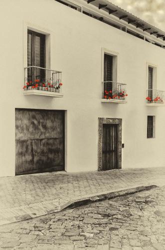 a white building with two windows and red flowers on balconies at Hotel Casa Gardenia in Quito