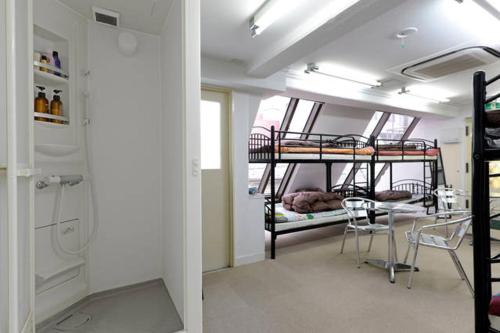 a room with two bunk beds and a table and chairs at Yushima Okachimachi Hotel in Tokyo
