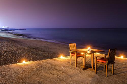 a table and chairs on the beach at night at Royal Beach Hotel & Resort in Dibba