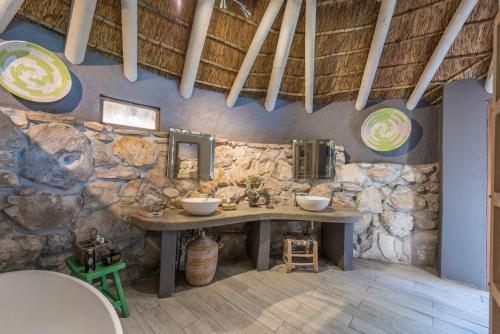 a stone bathroom with two sinks and a stone wall at Mosaic Lagoon Lodge in Stanford