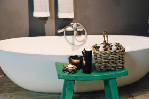 a bathroom with a bath tub and a basket on a table at Mosaic Lagoon Lodge in Stanford