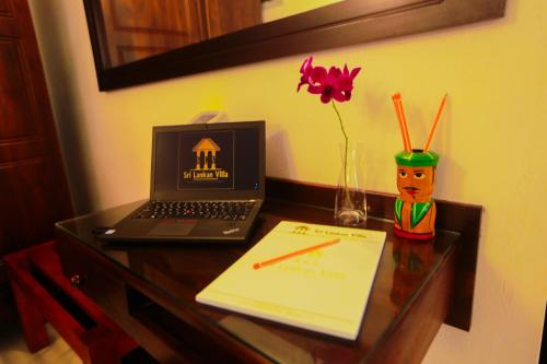 a desk with a laptop computer and a paper at SRI LANKAN VILLA in Galle