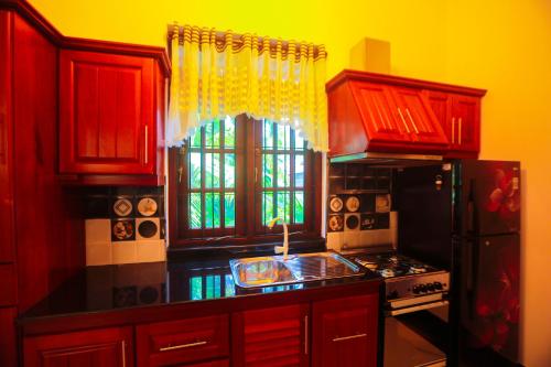 a kitchen with red cabinets and a black counter top at SRI LANKAN VILLA in Galle