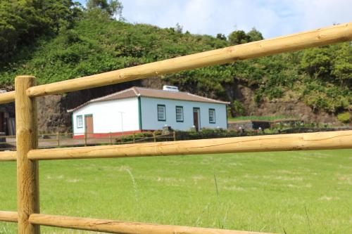 una valla de madera con una casa en el fondo en Casa da Avó - Turismo Rural, en Santo Espírito