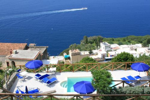 a view of the ocean from a resort with blue umbrellas at Villa Il Frantoio and Lilmar in Praiano