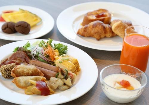 a table with plates of food and a glass of orange juice at Best Western Okinawa Onna Beach in Onna