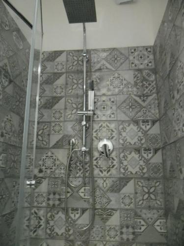 y baño con ducha y pared de azulejos. en Le vie del Centro, en Palermo