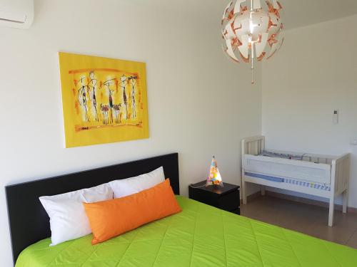 a bedroom with a green bed and a crib at Apartamento Praia Fuzeta in Fuzeta
