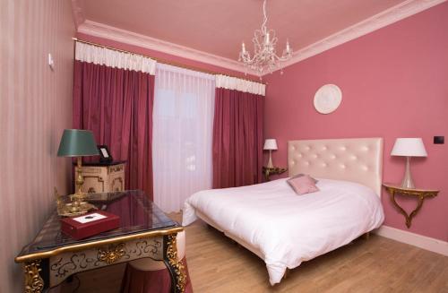 Un dormitorio con una cama blanca y una mesa con un cajón. en Villa Dufresne en Beynost