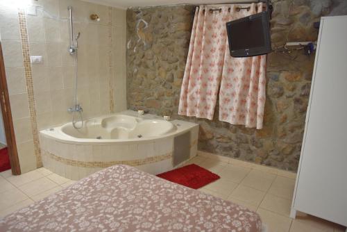 a bathroom with a bath tub and a tv in it at צימרים מעיין קצרין in Qasrîne