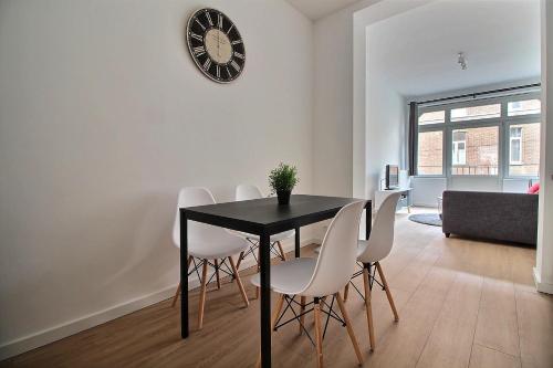 a dining room with a black table and white chairs at Rent a Flat - Bruxelles in Brussels