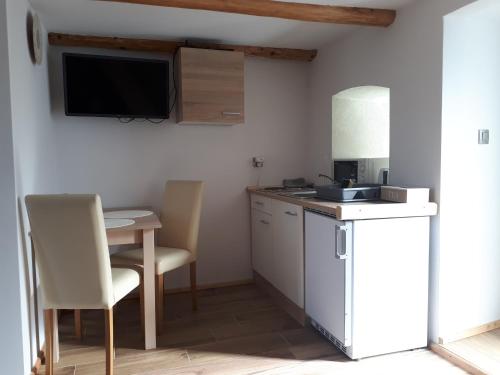 a small kitchen with a table and a tv on the wall at Apartament TA3 in Veľký Slavkov
