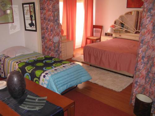 a bedroom with two beds and a desk and a table at Residencial Nosso Lar in Lisbon