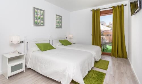 two beds in a white room with a window at Mafloras Luxury&Beach Apartment in Son Servera