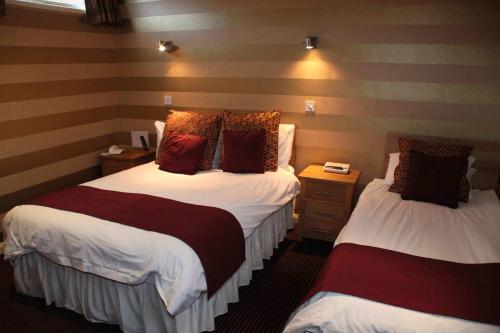a hotel room with two beds and two night stands at The Dog & Partridge Country Inn in Ashbourne