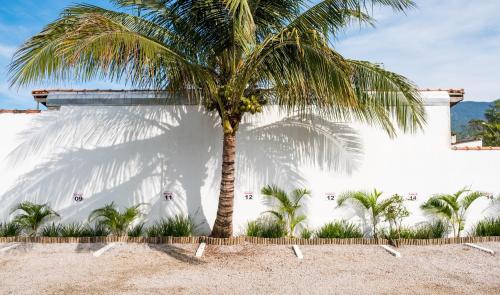 a palm tree in front of a white building at Recanto Maranduba in Ubatuba
