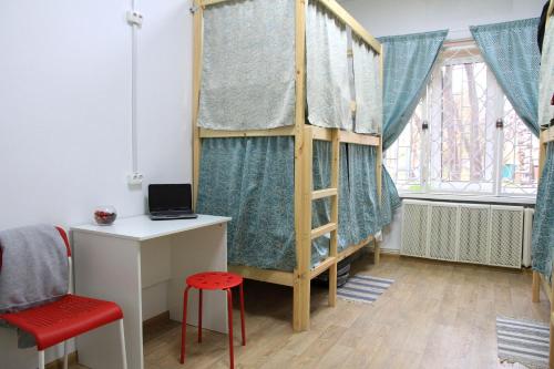 モスクワにあるHostel Izmaylovskiy Parkのロフトベッド、デスク、デスクが備わる客室です。