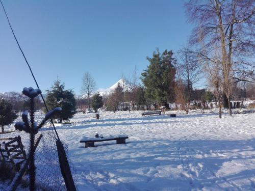 a park covered in snow with benches and trees at Cabañas Captren Andino in Curacautín