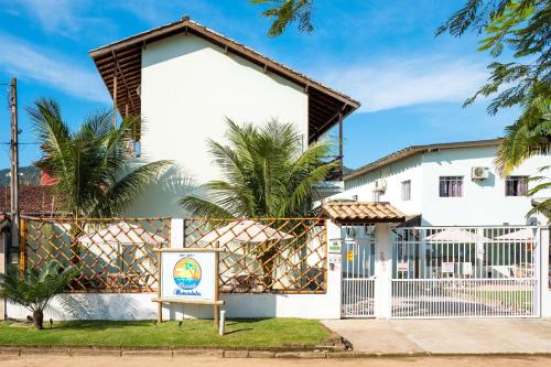 una casa blanca con una puerta y un cartel en Recanto Maranduba, en Ubatuba