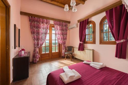 a bedroom with a bed with purple sheets and windows at Villas Marianna in Kalavárda