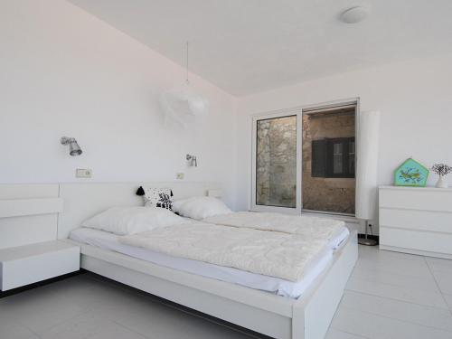 a white bedroom with a large bed and a window at Ferienhaus in Kavalos in Kávallos