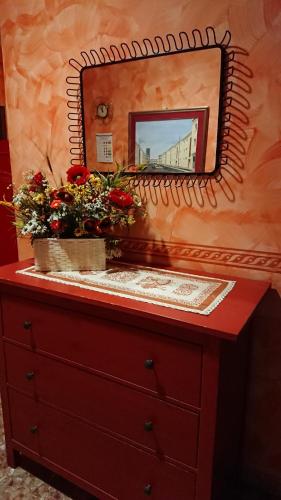 グイドニアにあるAlbergo Casa Lupiの花の入ったドレッサーの上に鏡