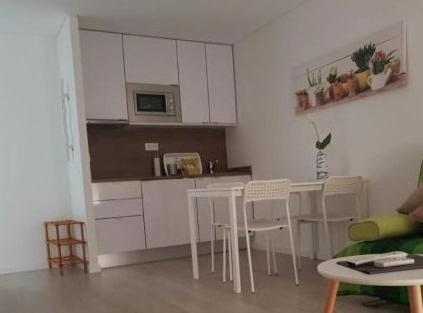 a kitchen with white cabinets and a table and chairs at Irís Apartment in Pombal