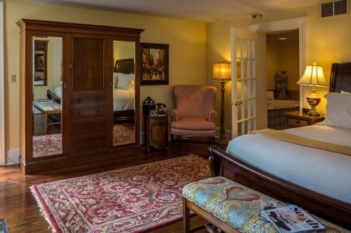 a bedroom with a bed and a chair and a mirror at The Gastonian, Historic Inns of Savannah Collection in Savannah