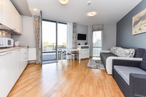 a kitchen and living room with a couch and a table at Apartamentai su terasa Elija in Šventoji