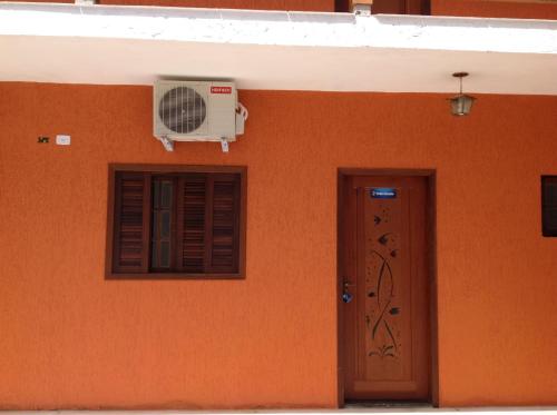 an orange wall with a fan and a door at Chalés Ubatuba 102 - P. Itaguá in Ubatuba