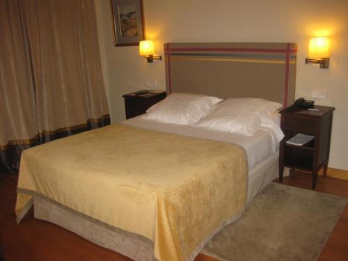 a hotel room with a bed and a phone on a night stand at Parador de Gijón in Gijón
