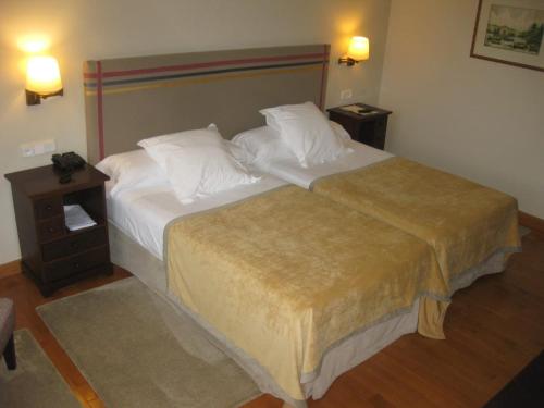 a hotel room with a large bed with white sheets and pillows at Parador de Gijón in Gijón