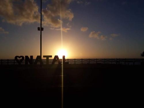 a sunset over a pier with a sign that reads vaan at Hotel Pousada Estacao Do Sol Natal in Natal
