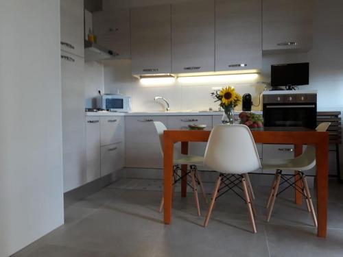 a kitchen with a wooden table and white chairs at casa Fantulìn Mare in Laigueglia