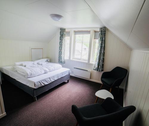 a bedroom with a bed and a chair and a window at Gudvangen Budget Hotel in Gudvangen