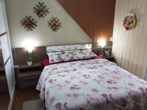 - une chambre avec un grand lit orné de fleurs roses dans l'établissement Apartamento no Centro de Canela, à Canela