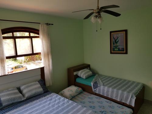a bedroom with two beds and a ceiling fan at Bertioga-Costa do Sol MK9 in Praia Guaratuba