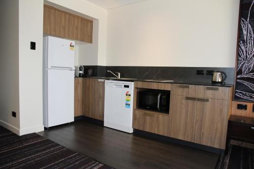 a kitchen with a white refrigerator and a microwave at Mantra Gladstone in Gladstone