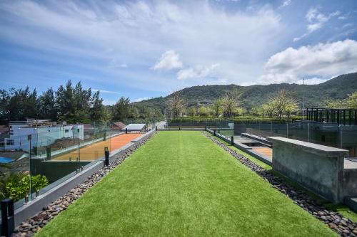 a tennis court on the roof of a building with grass at Glam Habitat - SHA Extra Plus in Kamala Beach