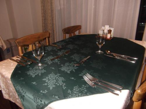 a table with a green table cloth with two wine glasses at Pension Green Lake in Gujo